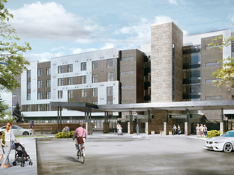A modern multi-story building with large windows and stone accents, featuring a covered entrance. Supporting the Delivery of Long-Term Care Homes in Ontario, it’s surrounded by trees as people walk, cycle, and push a stroller on a sunny day.